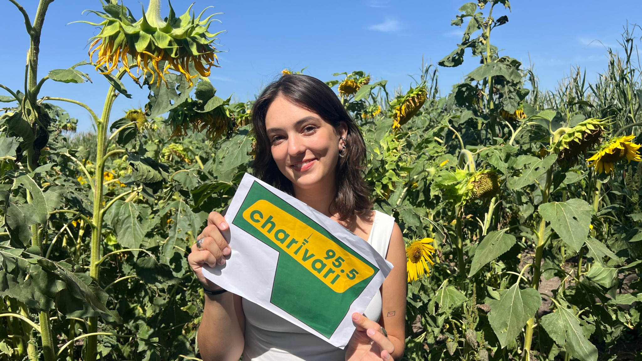 Junge Frau in einem Sonnenblumenfeld mit Radio Charivari 95.5 Motiv – GEOXIP Geobrandings und Ackerwerbung verbinden großflächige Markenkommunikation mit Blumen, Natur und Social-Media-Content